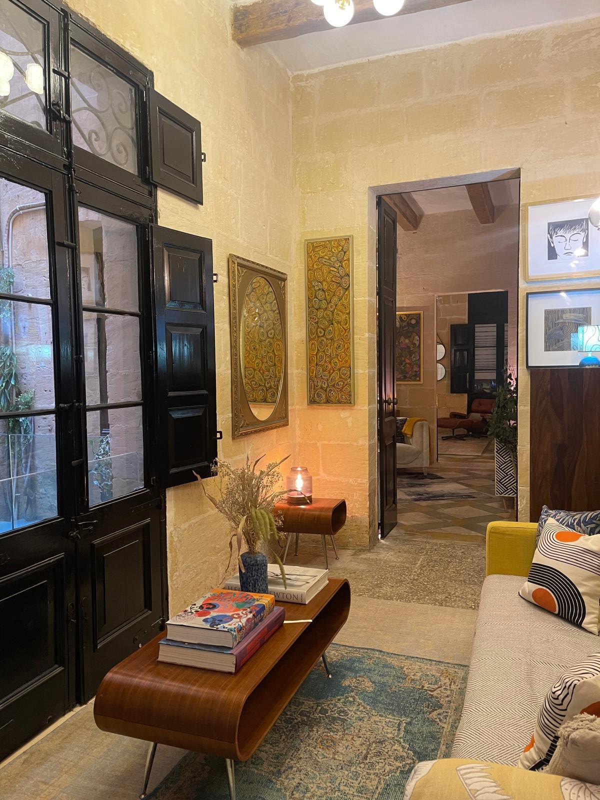 Black timber doors open onto a sitting room with paintings