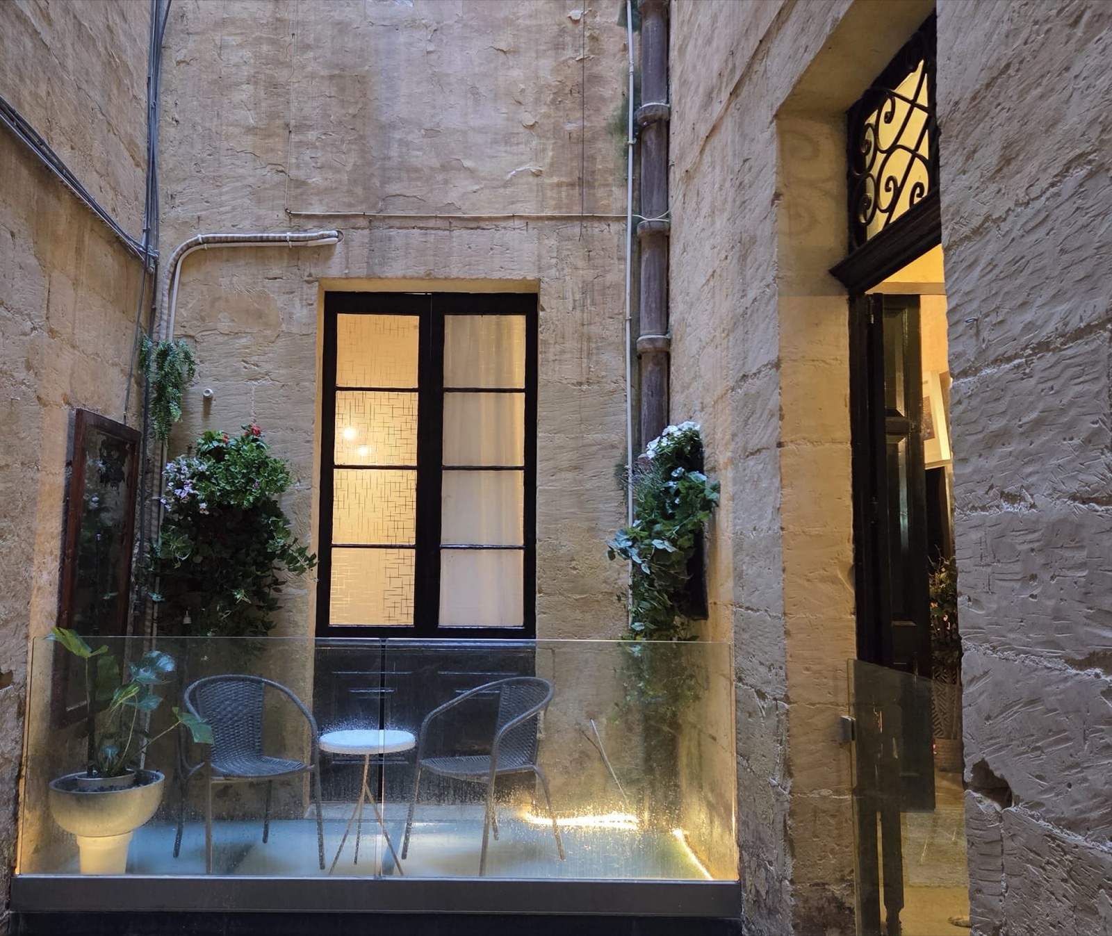 Limestone light well with a small table, plants and a lit window